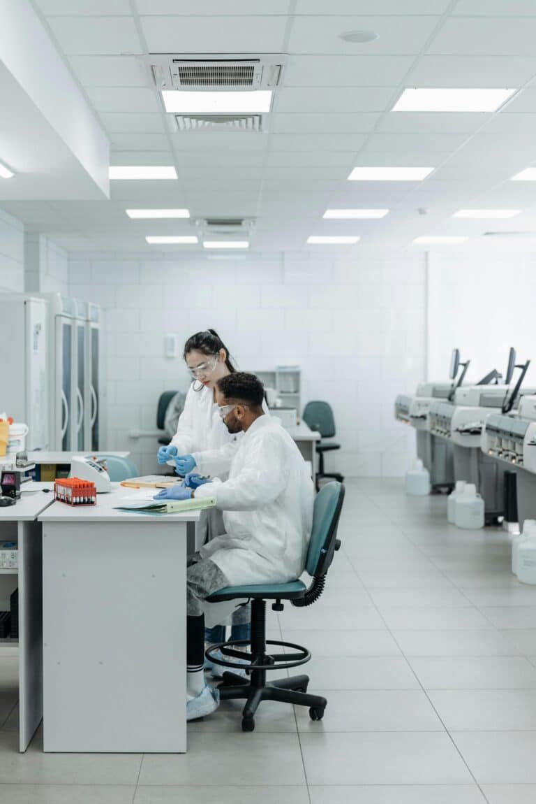 Two scientists in lab coats collaborate on experiments in a modern laboratory setting, analyzing data and samples.